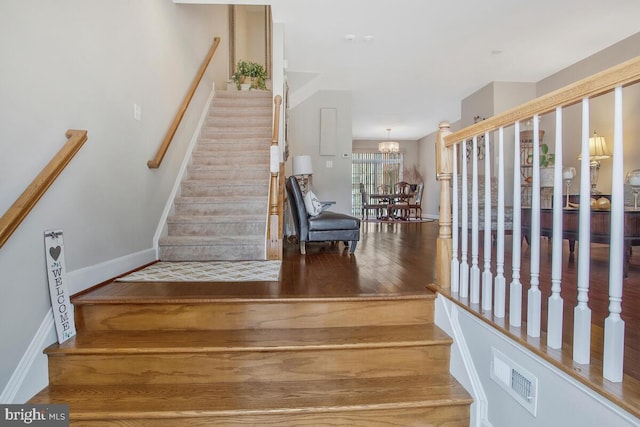 stairway featuring hardwood / wood-style floors and a notable chandelier