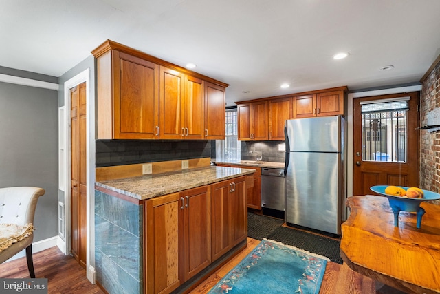 kitchen with dishwashing machine, stainless steel refrigerator, backsplash, dark hardwood / wood-style floors, and light stone counters