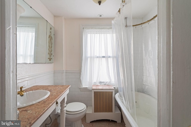 full bathroom featuring radiator heating unit, toilet, sink, and a wealth of natural light