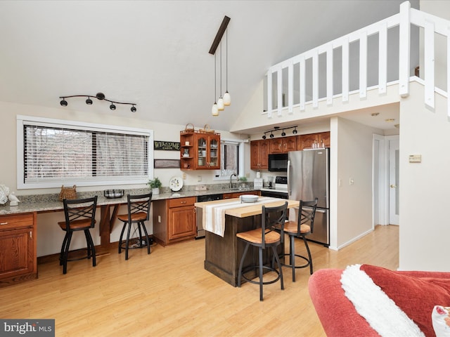 kitchen featuring stainless steel fridge, dishwasher, hanging light fixtures, a kitchen breakfast bar, and a center island