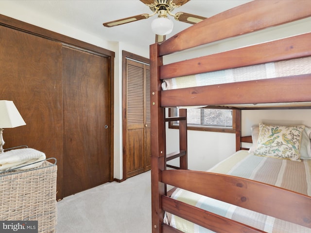 carpeted bedroom featuring multiple closets and ceiling fan