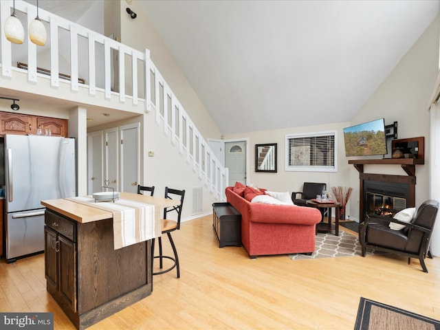 living room with high vaulted ceiling and light hardwood / wood-style flooring