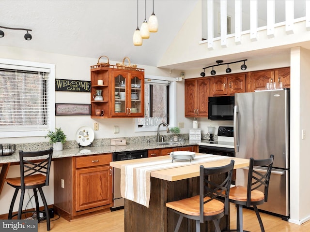 kitchen featuring dishwasher, sink, stainless steel fridge, hanging light fixtures, and electric stove