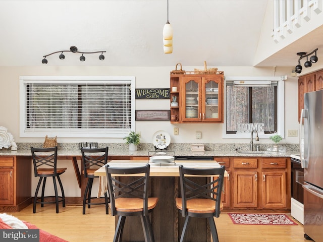 kitchen with stainless steel refrigerator, a breakfast bar, sink, and light wood-type flooring