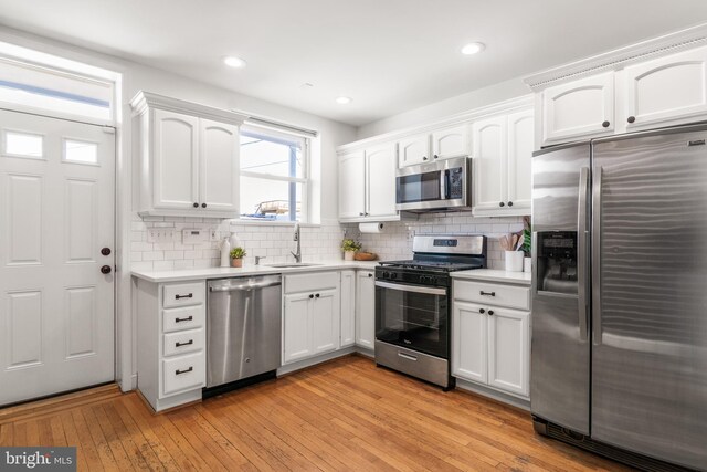 kitchen with white cabinetry, sink, stainless steel appliances, and light hardwood / wood-style floors