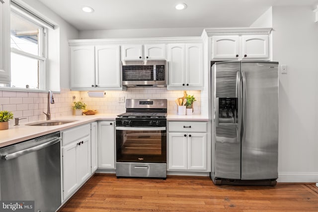 kitchen featuring white cabinetry, appliances with stainless steel finishes, sink, and light hardwood / wood-style flooring