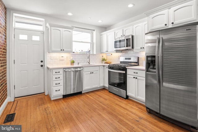 kitchen with white cabinetry, appliances with stainless steel finishes, sink, and light hardwood / wood-style flooring