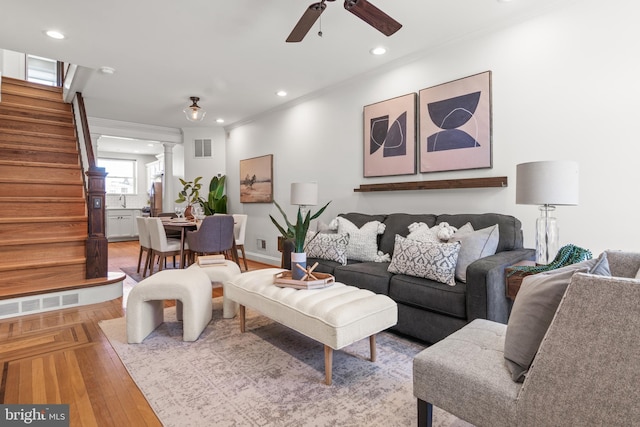 living room with crown molding, light hardwood / wood-style flooring, ceiling fan, and ornate columns