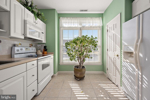 kitchen featuring white appliances, a wealth of natural light, light tile patterned floors, and white cabinets