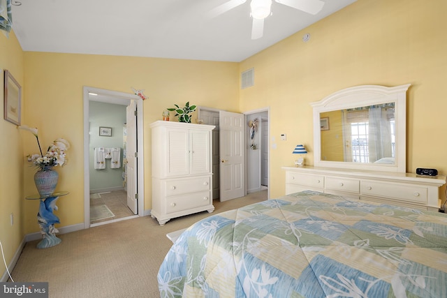 carpeted bedroom with vaulted ceiling, ceiling fan, and ensuite bath