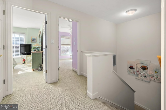 corridor with a wealth of natural light and light colored carpet