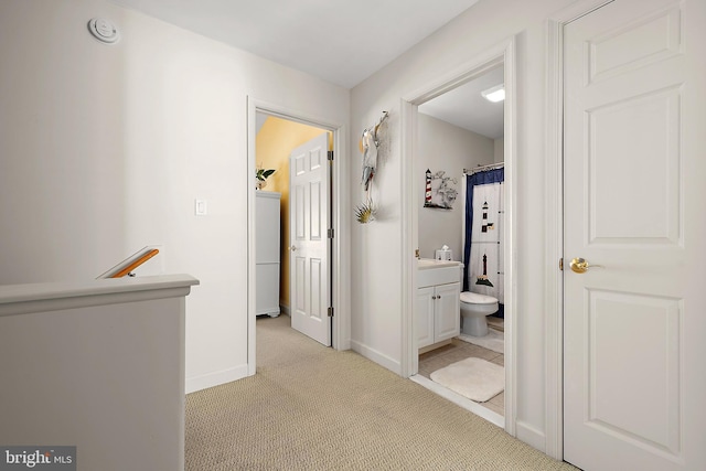 hallway with light colored carpet and washer / clothes dryer