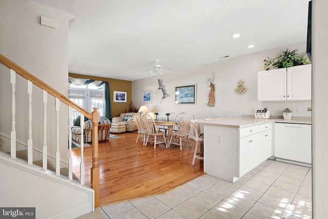 kitchen featuring dishwasher, white cabinets, light tile patterned floors, ceiling fan, and kitchen peninsula