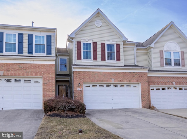 view of front of property with an attached garage, concrete driveway, and brick siding