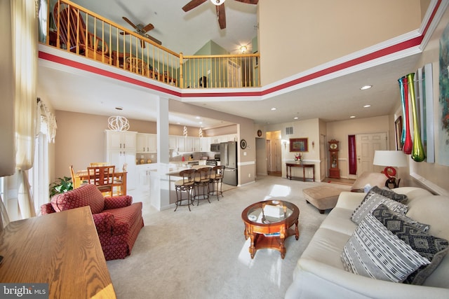 living room with visible vents, light colored carpet, a towering ceiling, ceiling fan, and recessed lighting