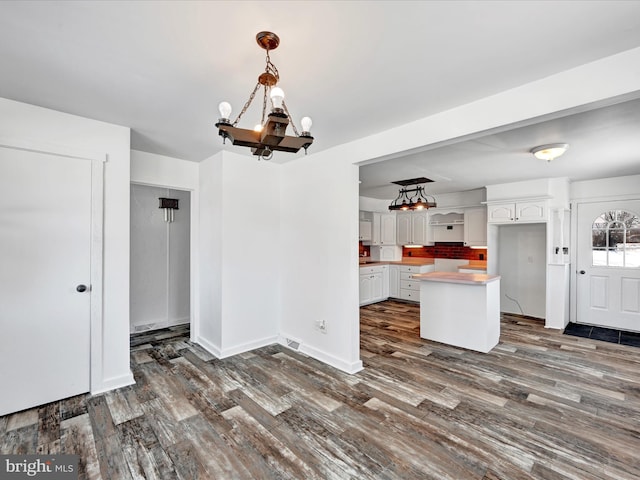 kitchen with dark hardwood / wood-style flooring, hanging light fixtures, white cabinets, and a kitchen island