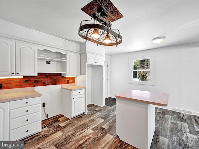 kitchen featuring dark wood-type flooring, white cabinets, and decorative light fixtures