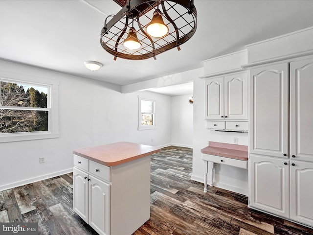 kitchen with hanging light fixtures, white cabinetry, a kitchen island, and dark wood-type flooring