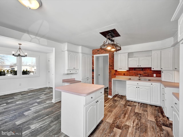 kitchen featuring hanging light fixtures, dark wood-type flooring, a center island, and white cabinets