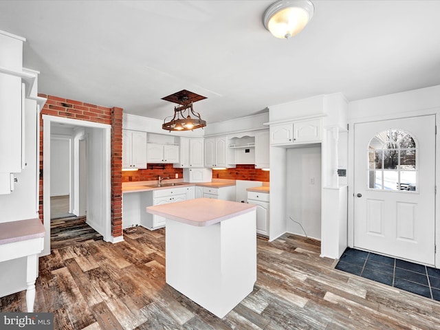 kitchen with sink, dark wood-type flooring, a center island, and white cabinets