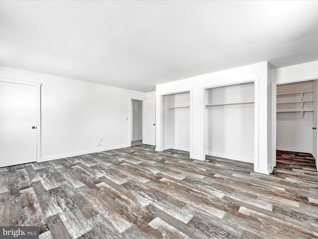 unfurnished bedroom featuring dark wood-type flooring and multiple closets