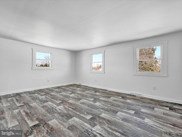 empty room featuring dark wood-type flooring and plenty of natural light