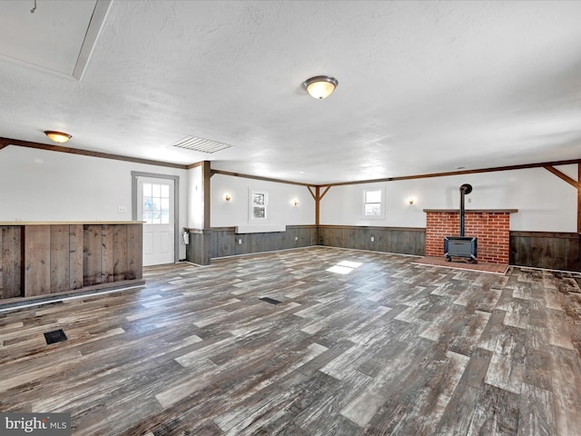 unfurnished living room with hardwood / wood-style flooring, a wealth of natural light, a textured ceiling, and a wood stove