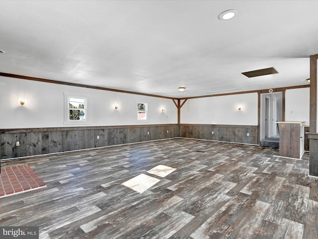 unfurnished living room featuring dark wood-type flooring, crown molding, and wood walls