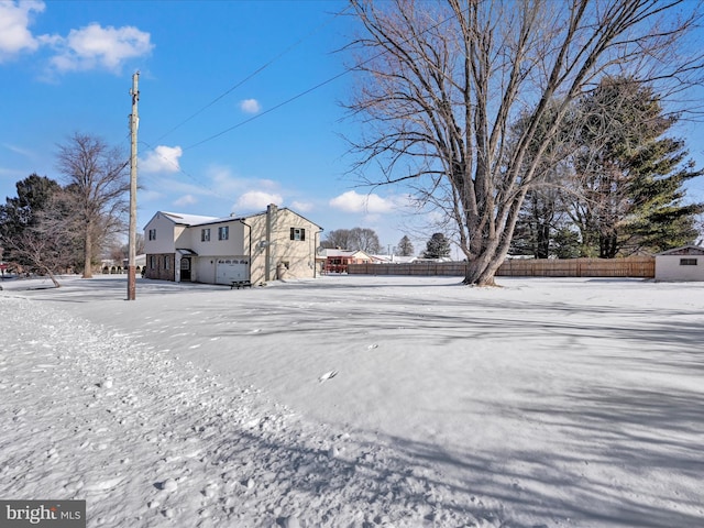 yard layered in snow featuring a garage