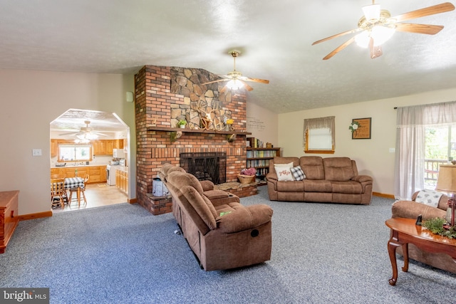 carpeted living room with lofted ceiling, a textured ceiling, a fireplace, and ceiling fan