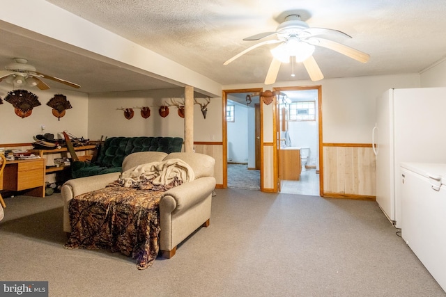 living room with ceiling fan, a textured ceiling, and wood walls