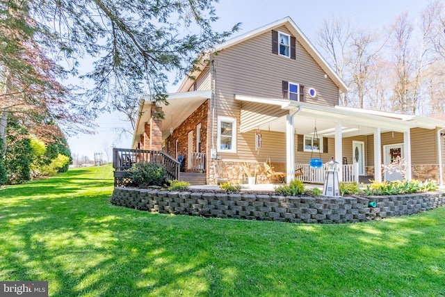 back of property featuring covered porch and a lawn