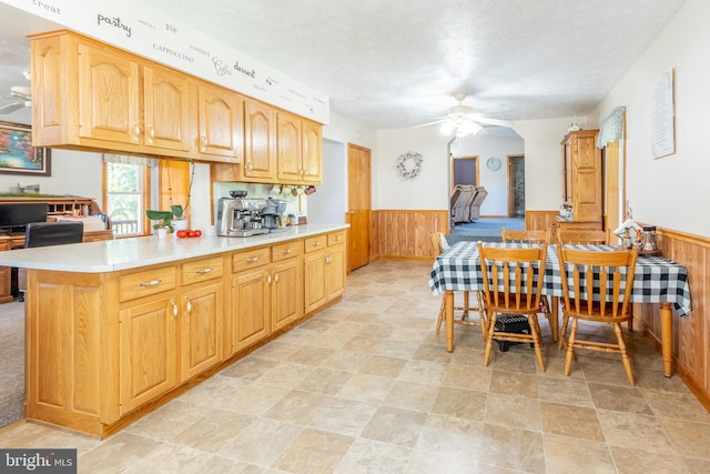 kitchen featuring a textured ceiling, ceiling fan, and wood walls