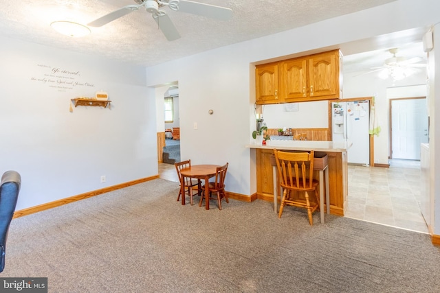 kitchen with a breakfast bar, light carpet, a textured ceiling, kitchen peninsula, and white fridge with ice dispenser