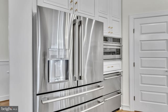 kitchen featuring high end fridge and white cabinetry