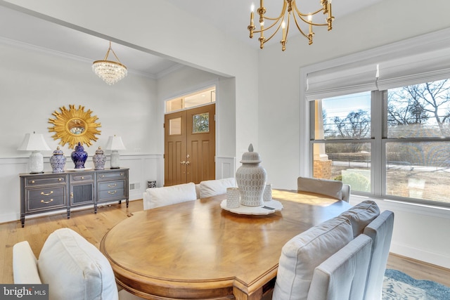 dining space with crown molding, light wood-type flooring, and an inviting chandelier