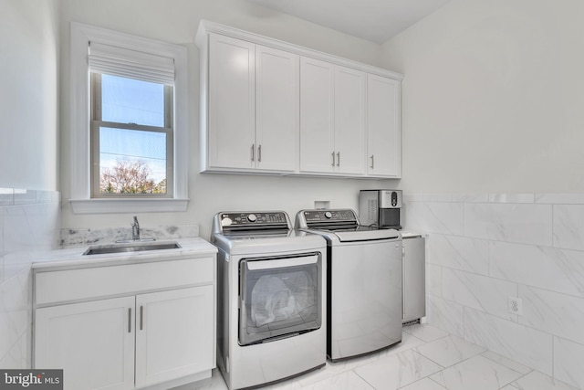 washroom with tile walls, sink, cabinets, and washer and dryer