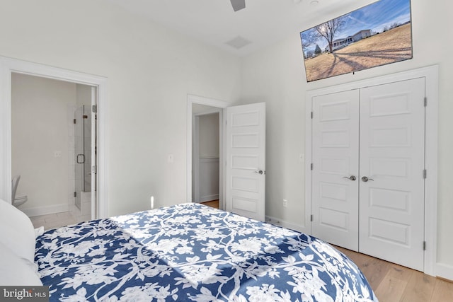 bedroom with ceiling fan, ensuite bath, light hardwood / wood-style floors, and a closet