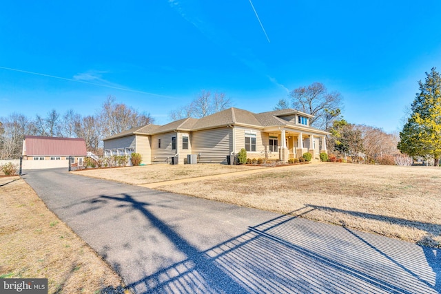 view of front of property with a garage, an outdoor structure, a front lawn, and covered porch