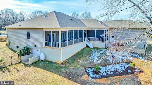 back of house featuring a garage, a lawn, and a sunroom