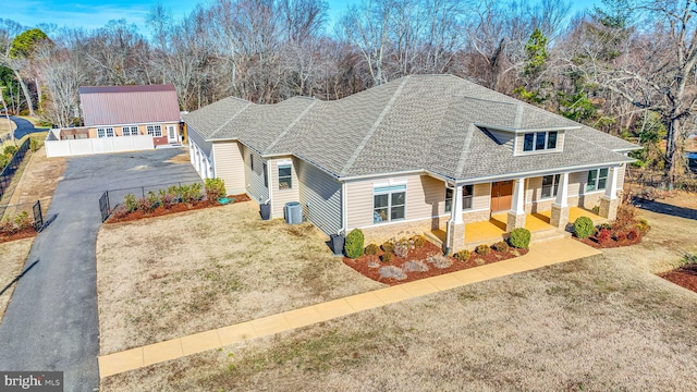 view of front of home featuring a porch, a garage, central AC unit, an outdoor structure, and a front yard