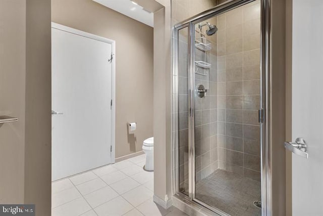 bathroom featuring a shower with door, tile patterned floors, and toilet