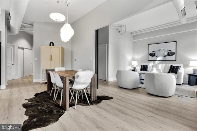 dining room featuring light hardwood / wood-style floors and a high ceiling