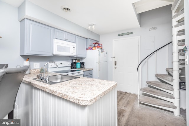 kitchen featuring sink, white appliances, light hardwood / wood-style floors, and kitchen peninsula