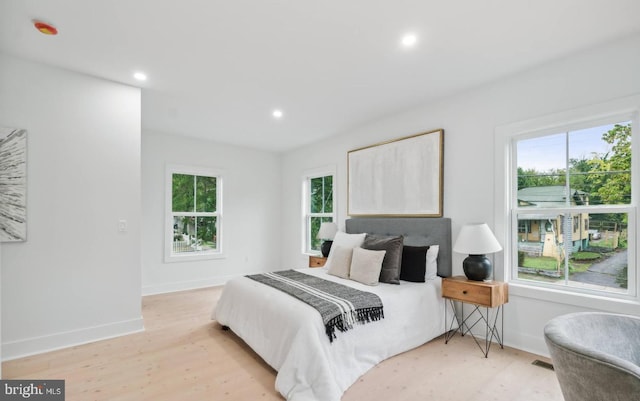 bedroom with multiple windows and light hardwood / wood-style floors