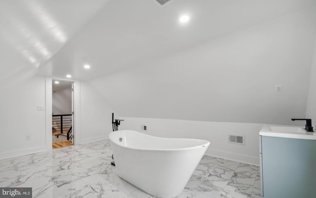 bathroom with a tub to relax in, vaulted ceiling, and vanity