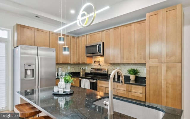 kitchen with appliances with stainless steel finishes, sink, a kitchen bar, decorative backsplash, and hanging light fixtures