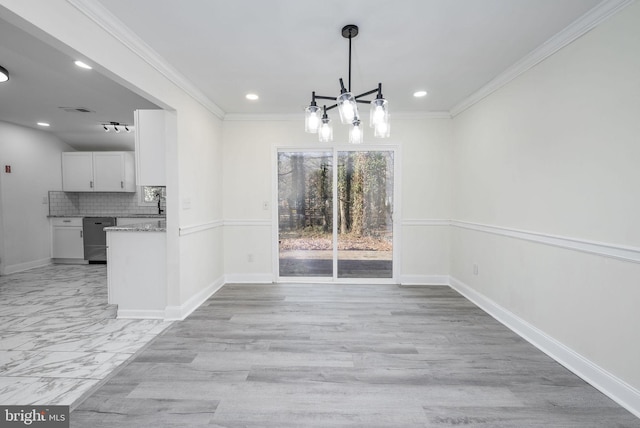 unfurnished dining area featuring crown molding, sink, and an inviting chandelier