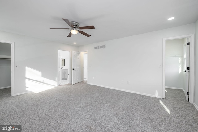 unfurnished bedroom featuring ceiling fan, carpet flooring, connected bathroom, a spacious closet, and a closet