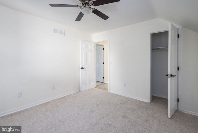 unfurnished bedroom featuring vaulted ceiling, light colored carpet, ceiling fan, and a closet